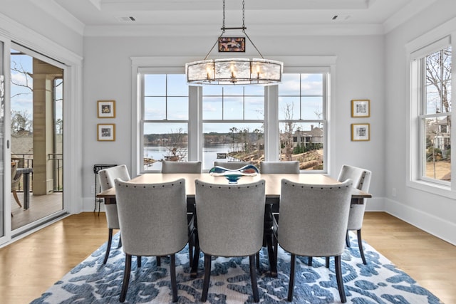 dining space with hardwood / wood-style flooring, ornamental molding, and a notable chandelier