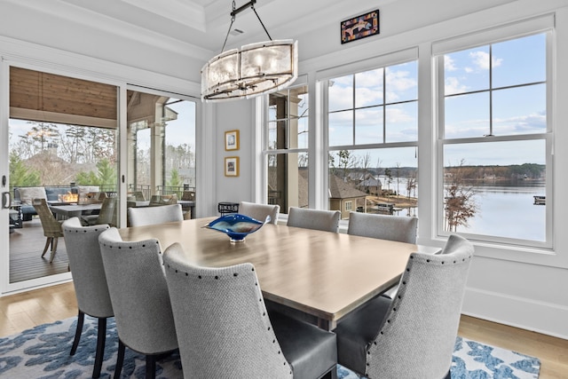 dining room with hardwood / wood-style flooring, a wealth of natural light, a chandelier, and a water view