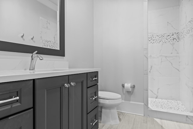 bathroom featuring vanity, toilet, and tiled shower