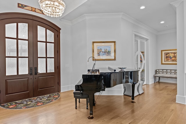 entrance foyer featuring french doors, crown molding, light hardwood / wood-style floors, and a notable chandelier