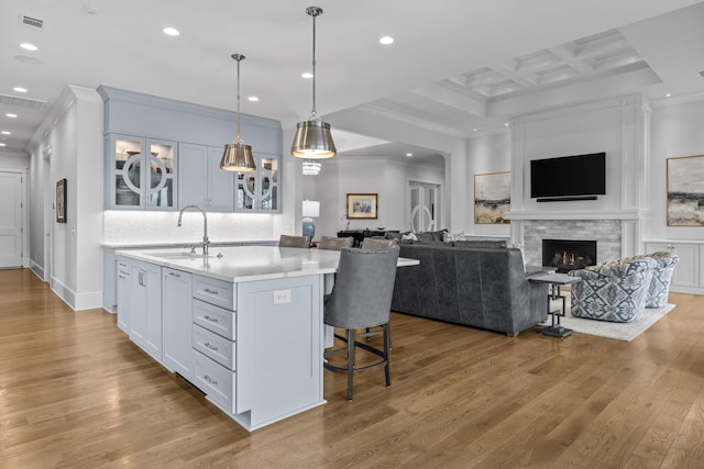 kitchen with an island with sink, sink, a breakfast bar area, white cabinets, and hanging light fixtures