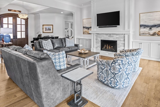 living room with a tile fireplace, crown molding, light hardwood / wood-style floors, and french doors