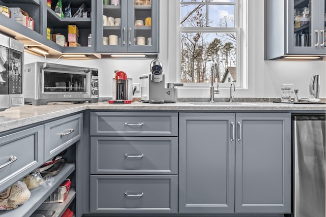 kitchen featuring light stone countertops, sink, and gray cabinetry