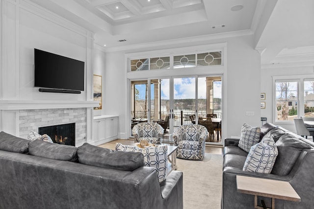 living room featuring a fireplace, crown molding, a wealth of natural light, and a towering ceiling