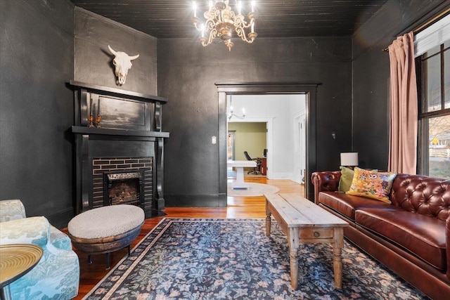 living room featuring a brick fireplace, hardwood / wood-style flooring, and a notable chandelier