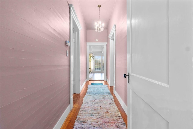 hall with hardwood / wood-style flooring and a notable chandelier