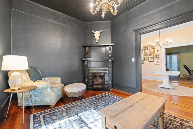 sitting room featuring a brick fireplace, dark hardwood / wood-style floors, and a notable chandelier