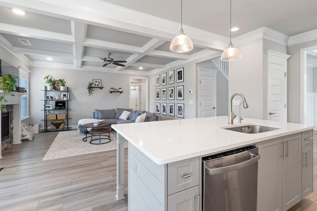 kitchen with hanging light fixtures, a center island with sink, sink, and stainless steel dishwasher