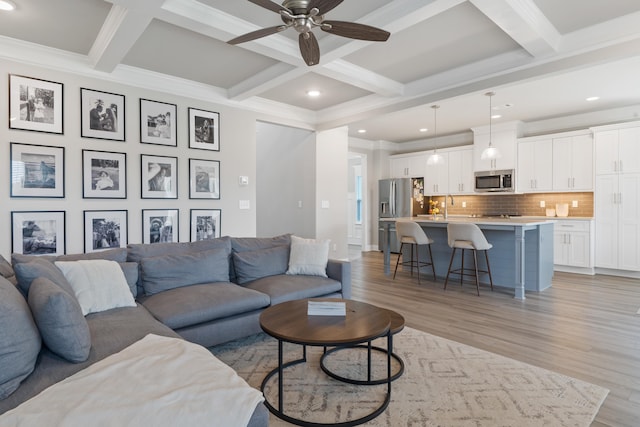 living room featuring sink, coffered ceiling, ceiling fan, beam ceiling, and light hardwood / wood-style flooring