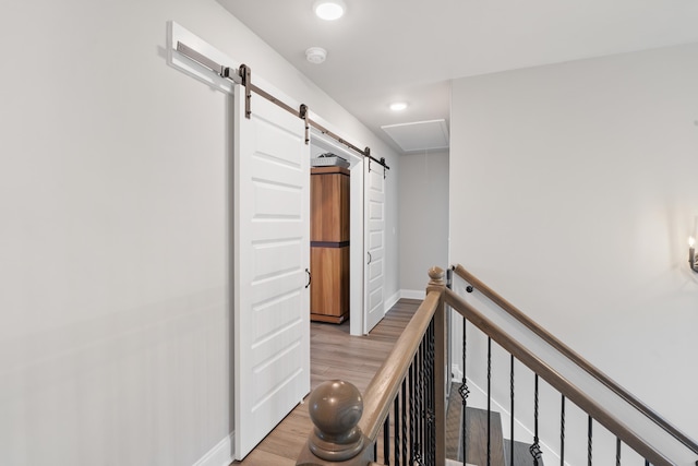 hallway with a barn door and light hardwood / wood-style flooring