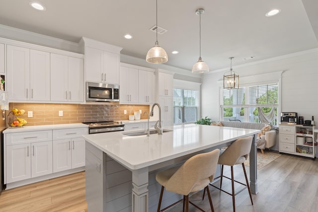 kitchen featuring white cabinetry, sink, stainless steel appliances, and a center island with sink