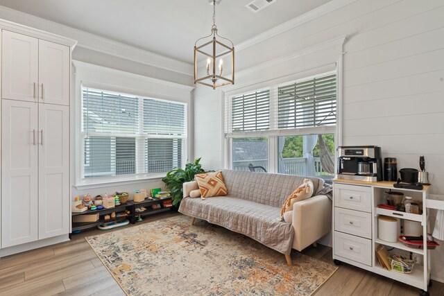 interior space featuring an inviting chandelier, ornamental molding, and light wood-type flooring