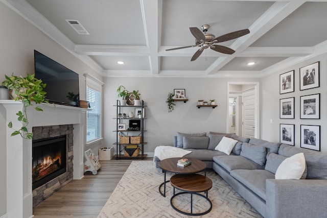 living room with ceiling fan, hardwood / wood-style floors, beam ceiling, coffered ceiling, and a fireplace