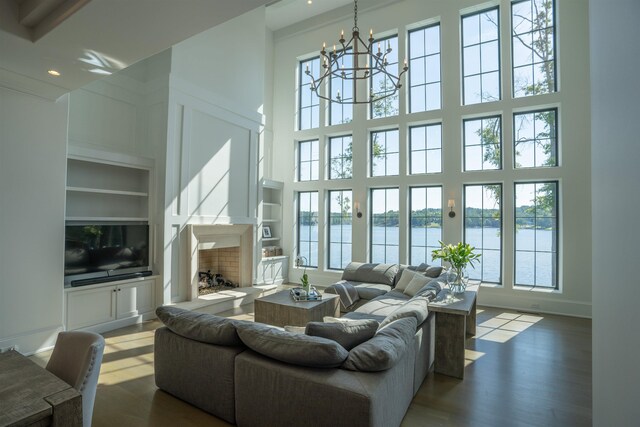 living room with a water view, a towering ceiling, and built in shelves