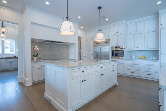 kitchen featuring pendant lighting, sink, appliances with stainless steel finishes, white cabinetry, and an island with sink