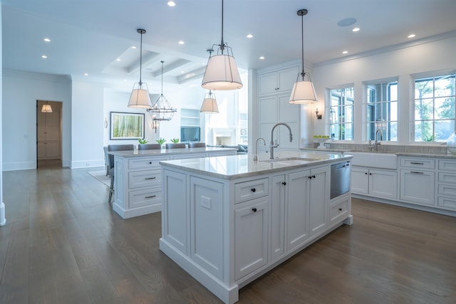 kitchen featuring white cabinetry, a kitchen island with sink, sink, and decorative light fixtures