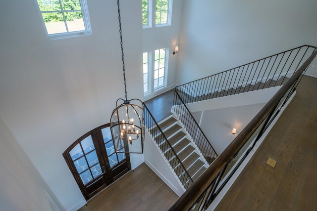 stairway with hardwood / wood-style flooring and an inviting chandelier