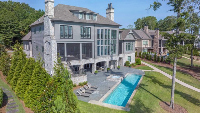 back of property with a swimming pool with hot tub, a patio, a sunroom, and a lawn