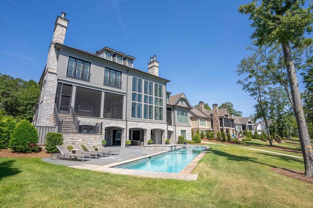 rear view of house with a patio, a sunroom, and a yard