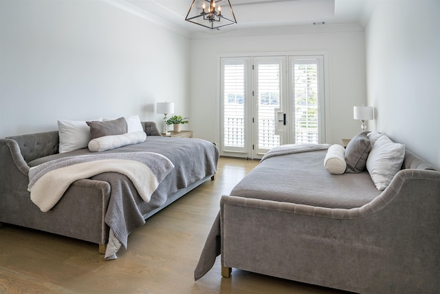 bedroom featuring hardwood / wood-style floors, access to outside, ornamental molding, and a chandelier