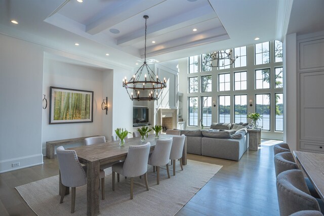 dining area featuring an inviting chandelier, dark hardwood / wood-style floors, a raised ceiling, and a high ceiling