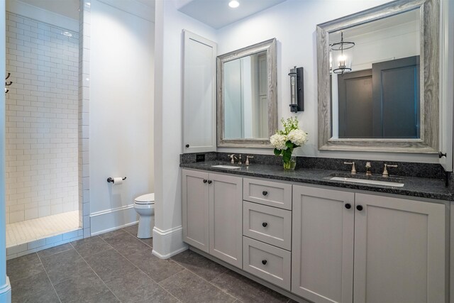 bathroom with vanity, toilet, and tiled shower