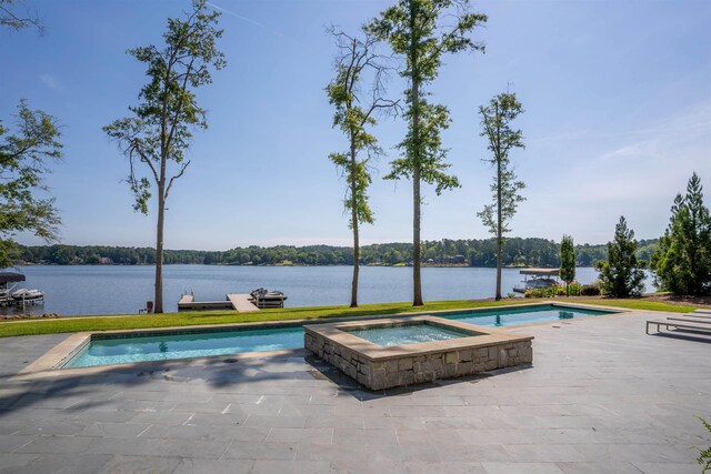 view of pool with an in ground hot tub, a water view, and a patio area