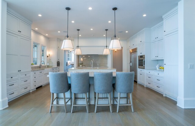 kitchen with a large island, a breakfast bar area, hanging light fixtures, stainless steel appliances, and white cabinets