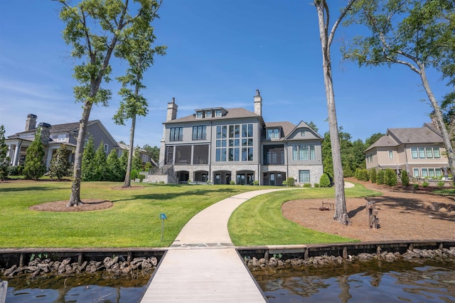 rear view of house featuring a water view and a lawn