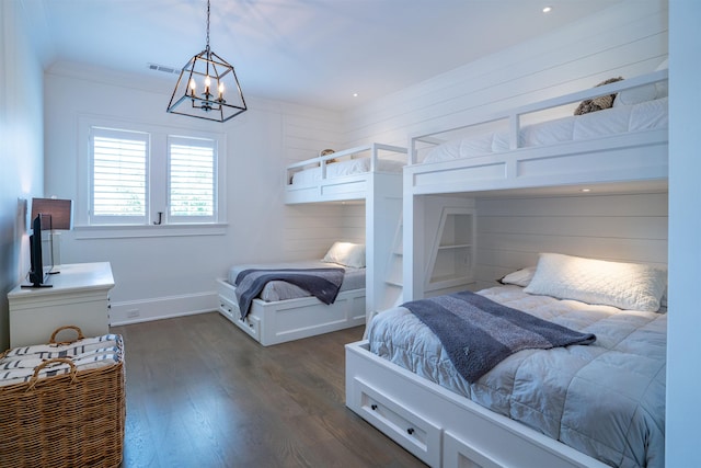 bedroom featuring dark wood-type flooring, wooden walls, and a chandelier