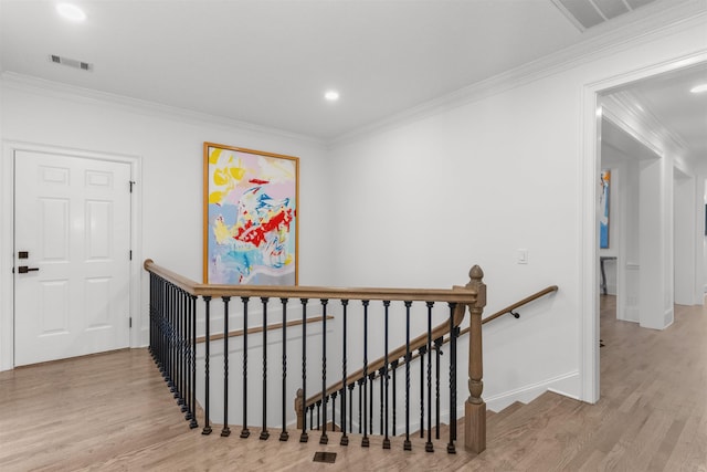 corridor featuring ornamental molding, visible vents, an upstairs landing, and wood finished floors