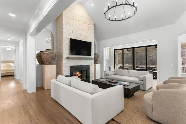 living room featuring wood finished floors, an inviting chandelier, vaulted ceiling, a stone fireplace, and recessed lighting