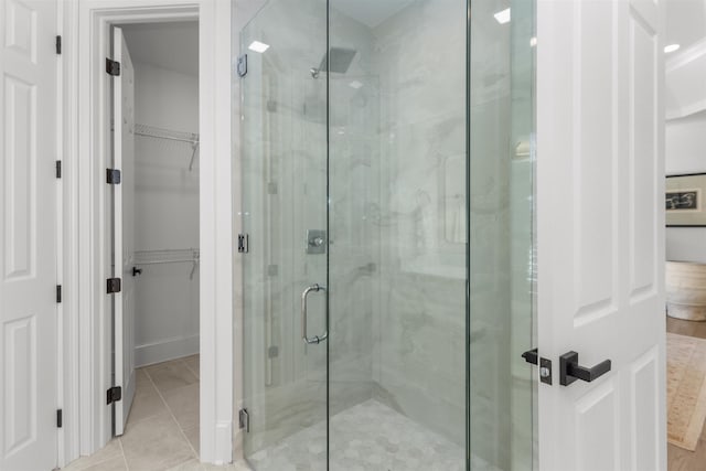 bathroom with a shower stall, a spacious closet, and tile patterned flooring