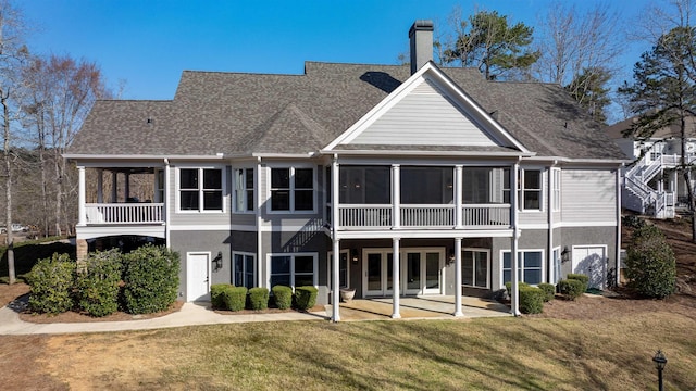 back of property with a patio, a sunroom, a chimney, a yard, and stucco siding