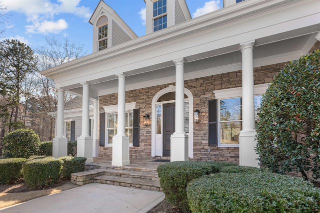 doorway to property featuring stone siding and a porch