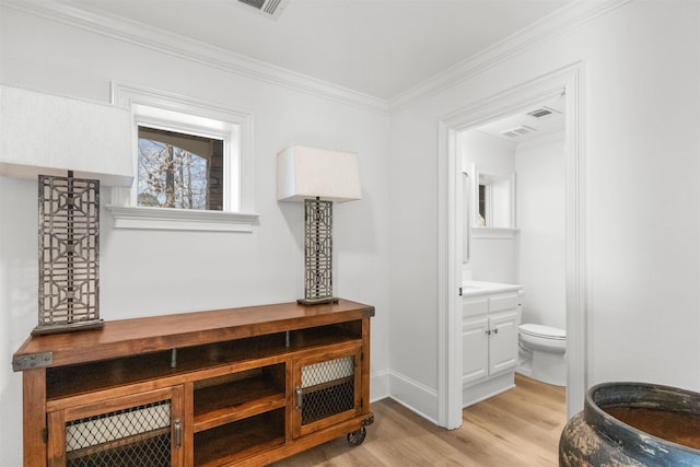 bathroom featuring toilet, ornamental molding, vanity, wood finished floors, and baseboards