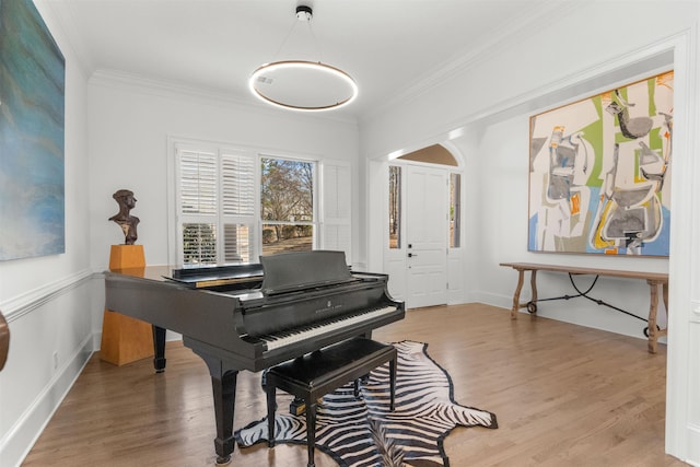 sitting room with ornamental molding, baseboards, and wood finished floors