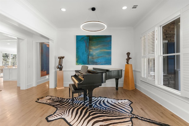 living area with baseboards, visible vents, crown molding, and wood finished floors