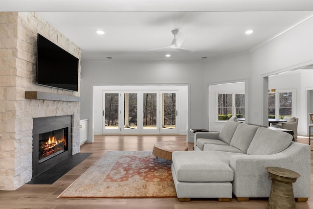 living room featuring recessed lighting, a fireplace, wood finished floors, a ceiling fan, and crown molding