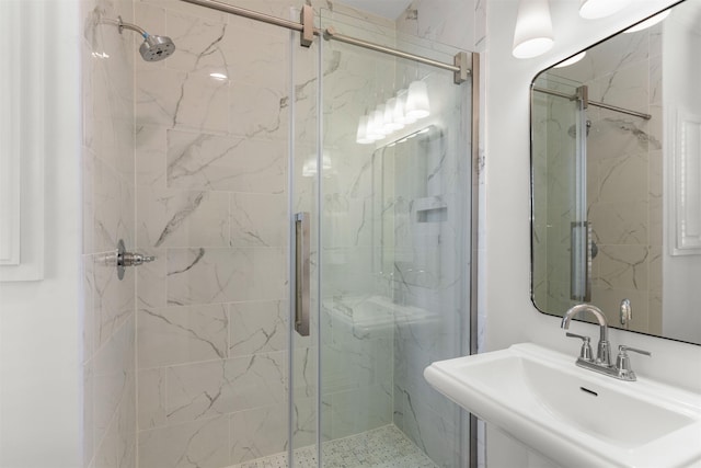 full bath with a marble finish shower and a sink