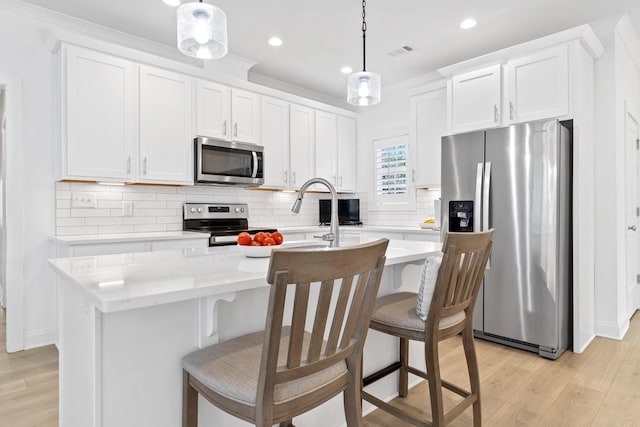 kitchen featuring light wood-style flooring, appliances with stainless steel finishes, an island with sink, and visible vents