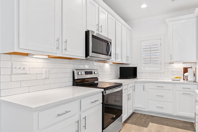 kitchen with white cabinets, recessed lighting, light countertops, stainless steel appliances, and backsplash