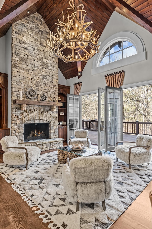 living room with a stone fireplace, hardwood / wood-style floors, high vaulted ceiling, a chandelier, and wood ceiling