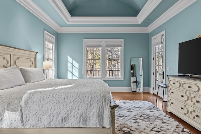 bedroom with crown molding, wood-type flooring, and a raised ceiling