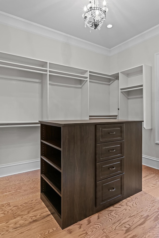 spacious closet featuring an inviting chandelier and light hardwood / wood-style flooring