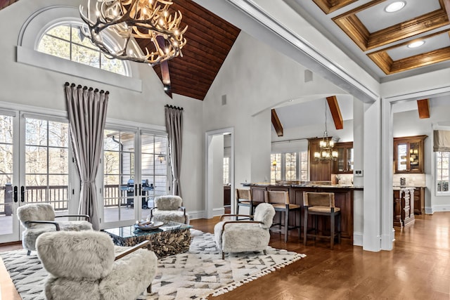 living room with french doors, a chandelier, dark hardwood / wood-style floors, a healthy amount of sunlight, and beam ceiling