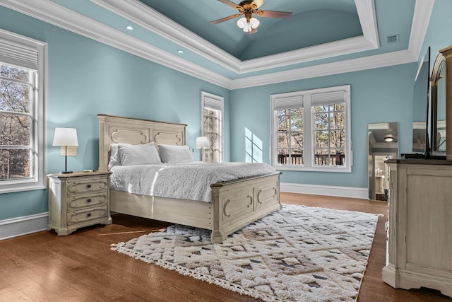 bedroom with multiple windows, crown molding, dark hardwood / wood-style floors, and a tray ceiling