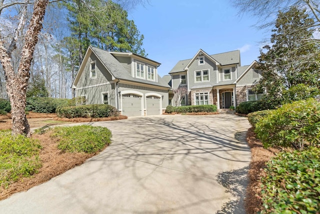 shingle-style home with stone siding, concrete driveway, and an attached garage