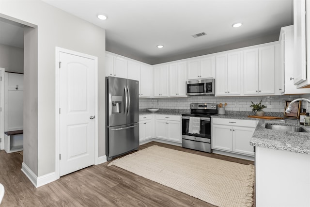 kitchen featuring light stone counters, sink, stainless steel appliances, and white cabinets