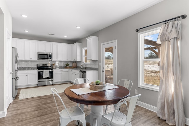 kitchen with sink, appliances with stainless steel finishes, light stone countertops, white cabinets, and decorative backsplash